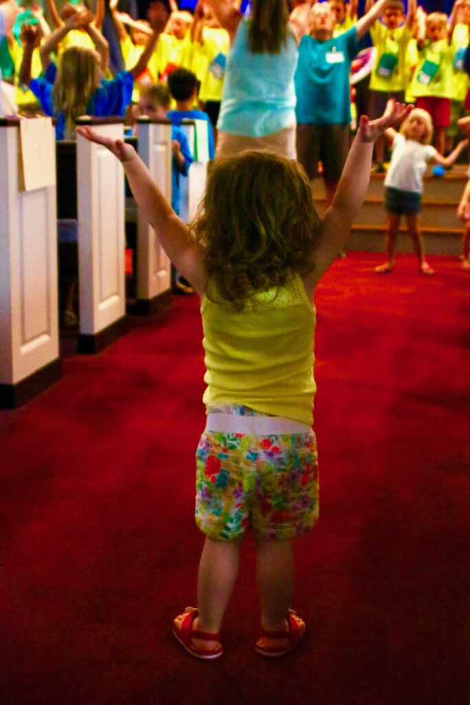 Toddler with hands raised high in joy.